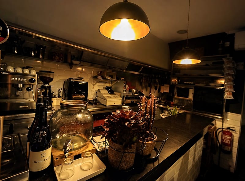 La barra con cafetera, lámpara colgante y azulejo blanco
